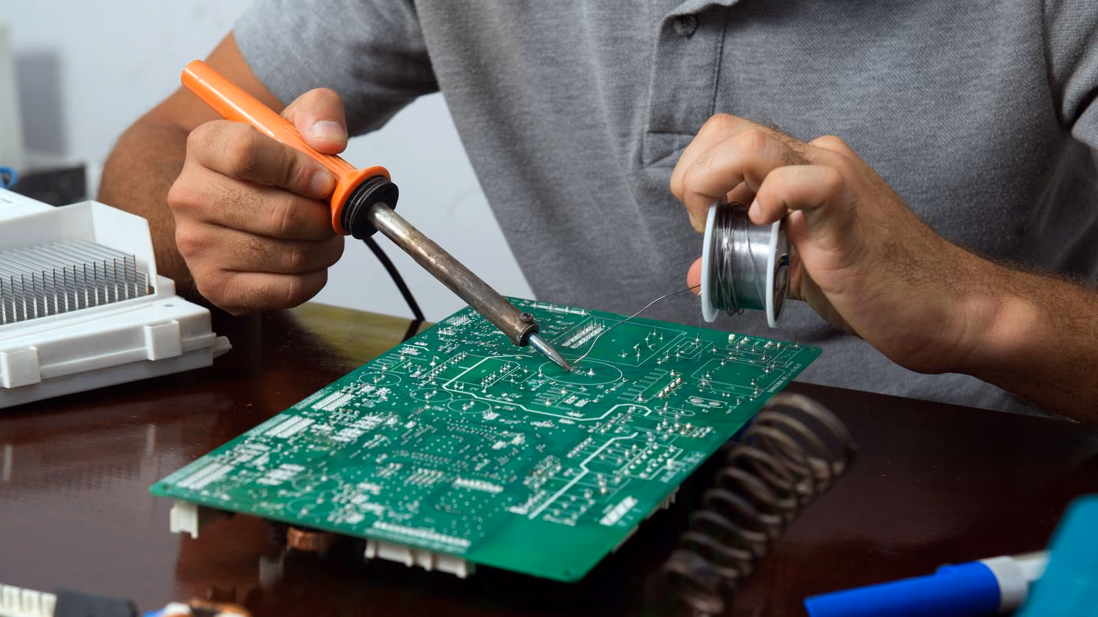 A circuit board held steady while a connection is reworked with an iron and solder