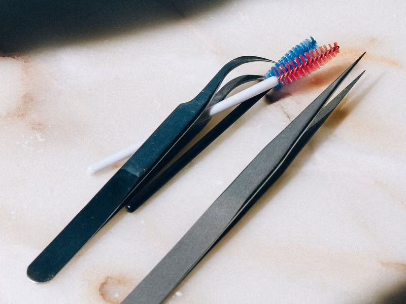 Precision tweezers and cleaning brushes resting on a marble surface